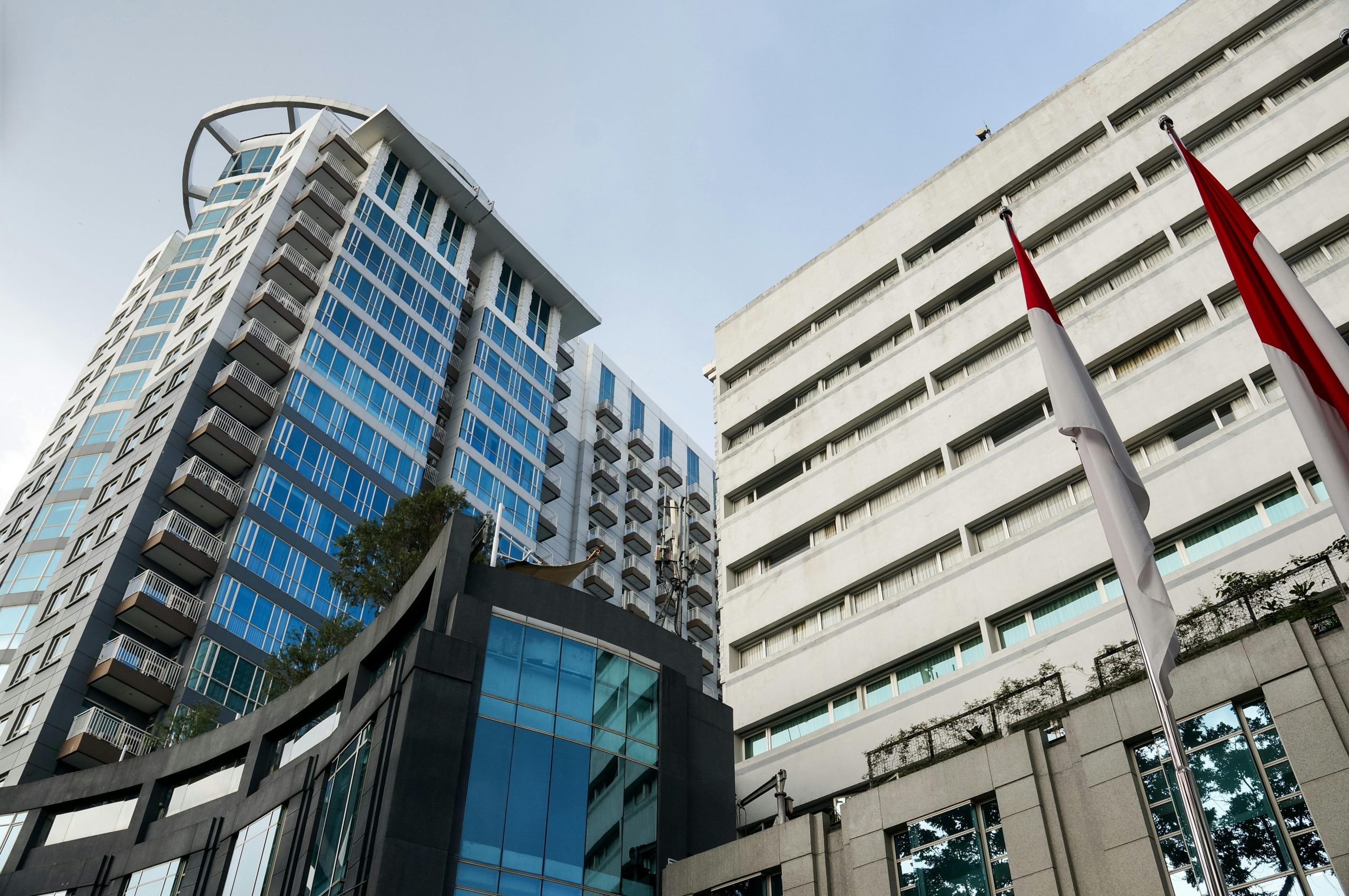 A striking view of modern high-rise buildings with red and white flags on a clear day.